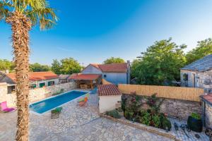 a house with a swimming pool and a palm tree at Villa Petrovi Dvori ZadarVillas in Benkovac