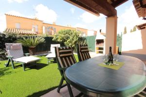 a patio with a table and chairs on the grass at LEON INMO Chalet Arenal - 15687 in Castelló d'Empúries