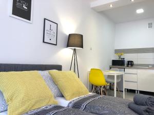 a bedroom with a bed and a yellow chair and a table at Apartament Szczęśliwa 13 - Plac Ratuszowy in Jelenia Góra