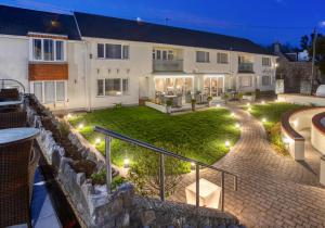 a home with a stone wall and a yard with lights at La Barbarie Hotel in St Martin Guernsey