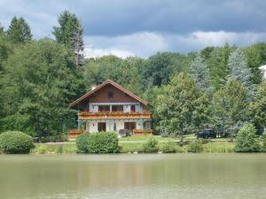 a house sitting on the side of a lake at Domaine de Chalétang in Belfort