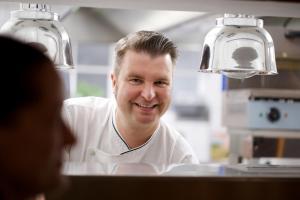 a man in a kitchen wearing a chef uniform at Hotel Reussischer Hof in Schmölln