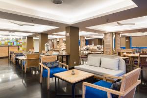 a restaurant with tables and chairs and a couch at Kuta Beach Hotel in Kuta