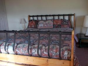 ein Schlafzimmer mit einem Bett mit einem Holzrahmen in der Unterkunft Ocean Ridge at Long Beach in Christchurch