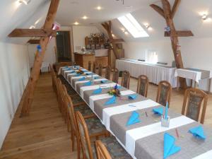 ein großes Zimmer mit einem langen Tisch mit blauen Servietten in der Unterkunft Landgasthof Deinert in Parchen