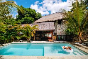 a villa with a swimming pool in front of a house at La Cabane in Jimbaran