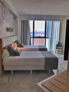 two beds in a hotel room with a large window at Hotel Madeira Centro in Benidorm