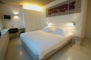 a bedroom with a large white bed and a desk at Hotel Matelote in Antwerp