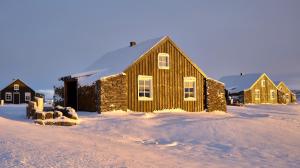 eine Holzscheune auf einem schneebedeckten Feld mit Häusern in der Unterkunft Torfhús Retreat in Selfoss