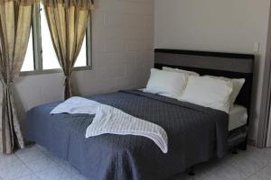 a bedroom with a bed with a blue comforter and a window at Lotopa Home in Apia