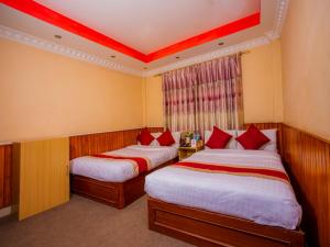 a bedroom with two beds and two lamps at OYO 305 Hotel Gauri in Pashupatināth