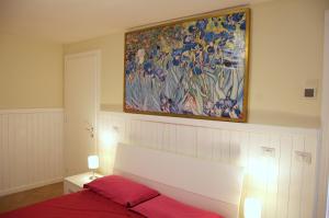 1 dormitorio con una pintura colgada sobre una cama en Casale Il Vento, en Abbadia di Montepulciano