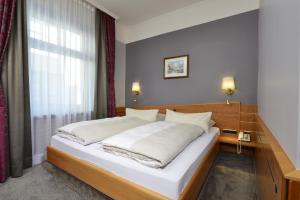 
a bedroom with a large bed and a large window at Hotel Torbräu in Munich
