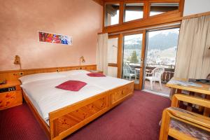 a bedroom with a large bed and a balcony at T3 Hotel Mira Val in Flims