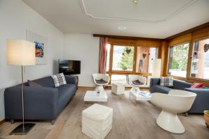 a living room with two blue couches and a tv at T3 Hotel Mira Val in Flims