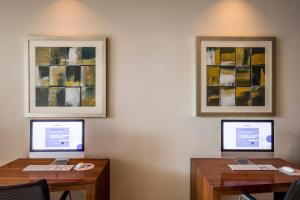 a desk with two monitors and two laptops at Novotel Deira City Centre in Dubai