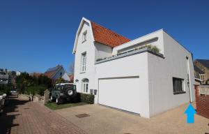 ein weißes Haus mit einer großen weißen Garage in der Unterkunft Vakantiewoning De Konijnenweg in De Panne