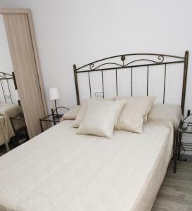 a white bed with white sheets and pillows at La CaSa De Su in Gijón