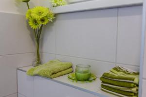 a shelf with a vase of yellow flowers and a glass at Anna Maria Medjugorje in Međugorje
