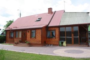 een houten huis met een rood dak bij Kama Pokoje Gościnne in Białowieża