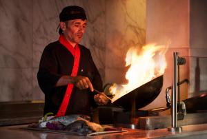 Ein Mann, der Fleisch auf einem Grill mit Flammen kocht. in der Unterkunft Coral Sea Holiday Resort and Aqua Park in Sharm El Sheikh