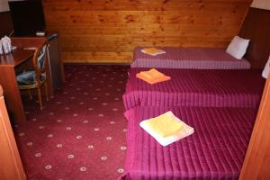 a room with two beds with purple sheets and a desk at семеен хотел Визаж in Yambol +16 photos