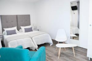 1 dormitorio blanco con 1 cama y 1 silla azul en Hostal Castillo, en San José de La Rinconada