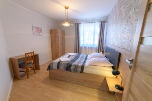 a bedroom with a bed and a desk and a window at Apartamenty Rodzinne Zdrojowe in Kudowa-Zdrój