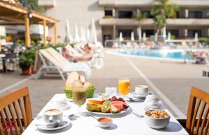 una mesa con comida y bebida junto a una piscina en GF Fañabe en Adeje