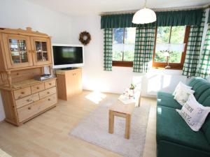 a living room with a green couch and a tv at Apartment close to the ski area in Hüttschlag