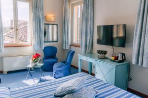 sypialnia z łóżkiem, telewizorem i krzesłem w obiekcie Hostellerie Du Golf w mieście Pecetto