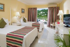 um quarto de hotel com duas camas e uma televisão em SeaGarden Beach Resort - All Inclusive em Montego Bay