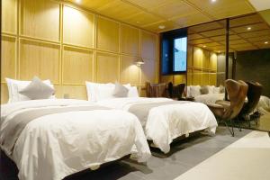 um quarto de hotel com três camas com lençóis brancos em Astro Hotel em Yongin