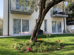 a tree in front of a house with flowers at Appartamenti Villa Andrea in Garda