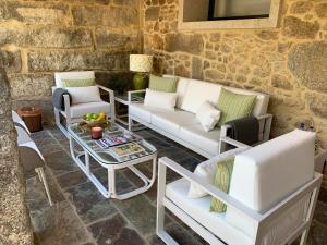 a patio with white couches and a table and chairs at Casa Herreria in Caldas de Reis