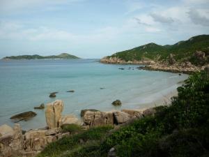 una spiaggia con rocce e l'oceano e le montagne di LY'S Căn hộ Homestay Phan Rang-2pn a Phan Rang-Tháp Chàm