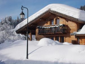 a snow covered house with a light pole in front of it at Chalet Jonquille in Les Gets