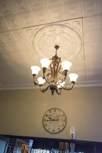 a ceiling with a chandelier and a clock on a wall at Border Hotel in Jan Kempdorp