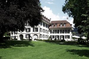 a large white house with a large grass yard at Hotel Schloss Hünigen in Konolfingen