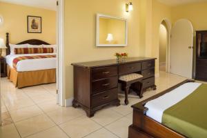 a bedroom with a dresser and a bed with a mirror at SeaGarden Beach Resort - All Inclusive in Montego Bay