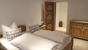 1 dormitorio con 1 cama con sábanas y almohadas blancas en St Lukas Apartments en Oberammergau