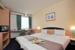 a hotel room with two beds and a tv at Plaza Inn Berlin Süd Ludwigsfelde in Ludwigsfelde