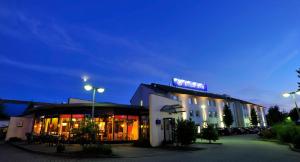 a hotel with a sign on top of it at night at Plaza Inn Berlin Süd Ludwigsfelde in Ludwigsfelde