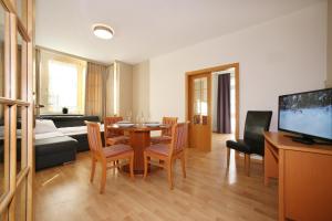 salon ze stołem, krzesłami i telewizorem w obiekcie City Apartments Mozart w mieście Zell am See