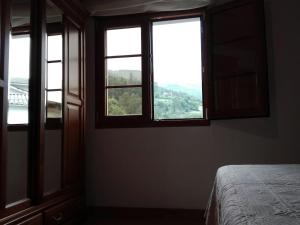 a room with three windows and a bed in it at Casa de aldea Amezaga in Taramundi