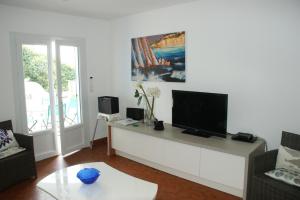a living room with a flat screen tv on a cabinet at l'ecrin bleu in Les Issambres