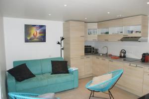 a living room with a blue couch and a kitchen at l'ecrin bleu in Les Issambres