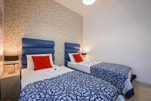 a bedroom with two beds with blue and red pillows at San Martino Rooms in Pula