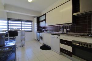 - une cuisine avec des placards blancs et un lave-linge/sèche-linge dans l'établissement Tim House, à Olhão