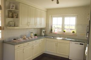 a kitchen with white cabinets and a sink and a window at 'Op de Borgt' met Finse Grill Kota in Wellen